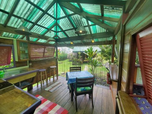 a conservatory with a table and chairs in a house at Heimanarii's Lodge - Fare Fetia in Haapiti