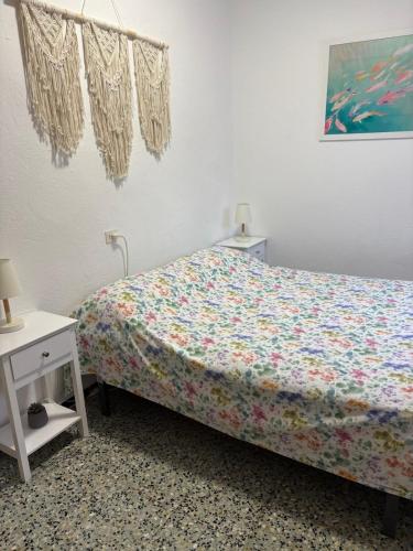 a bedroom with a bed with a floral bedspread and a table at Casa Calma in L'Escala