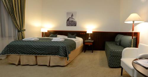 a hotel room with a bed and a chair at Hotel Grand in Český Krumlov