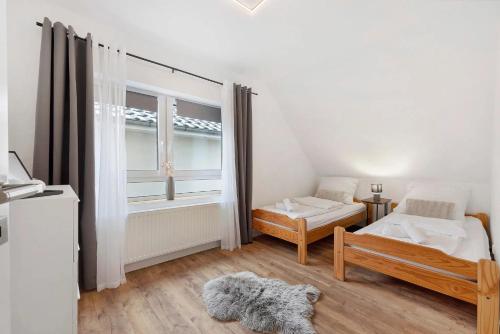 a white bedroom with a bed and a window at P & A Ferienwohnung in Soltau