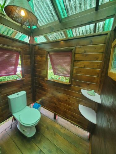 a bathroom with a toilet and two windows at Heimanarii's Lodge - Fare Fetia in Haapiti