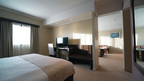 a hotel room with a bed and a desk with a television at Hathor Concordia in Concordia