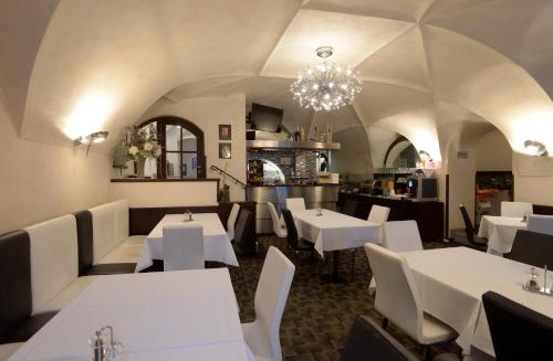 a restaurant with white tables and chairs and a chandelier at Hotel Grand in Český Krumlov