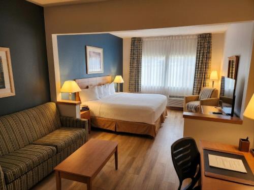 a hotel room with a bed and a couch at Baymont by Wyndham Helena in Helena