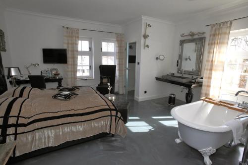 VILLA ADELEes BOUTIQUE HOTEL في آلسفلد: غرفة نوم مع سرير وحوض استحمام ومغسلة