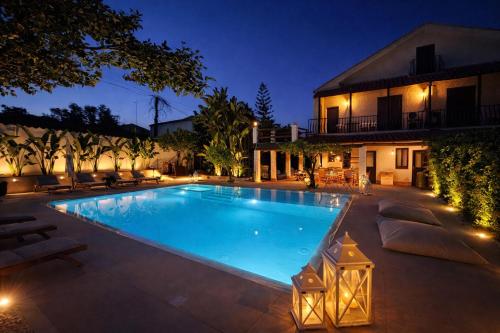 a swimming pool in front of a house at night at Villa Elisa - Luxury and Style by the Sea in Fontane Bianche