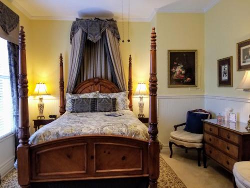 a bedroom with a wooden bed with a canopy at The Queen Anne Bed & Breakfast in Natchitoches