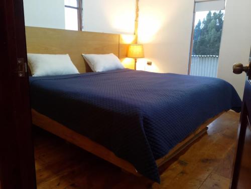 a bedroom with a large bed with a blue comforter at Cabaña Ortiz in Guatavita