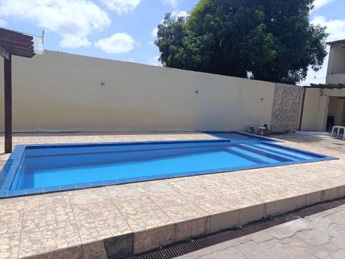a blue swimming pool in front of a white wall at Studio Jéssica in Arunta
