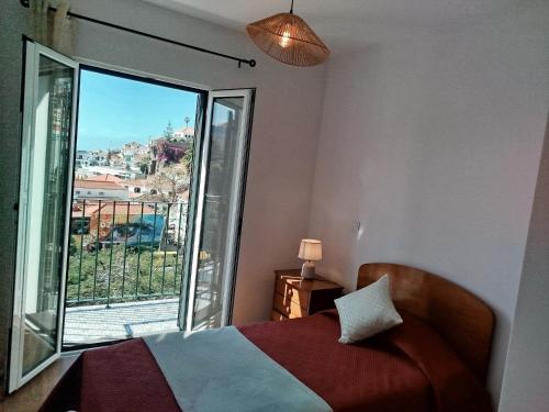 a bedroom with a bed and a large window at Baía dos Lobos in Câmara de Lobos