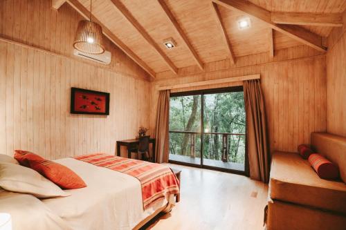 a bedroom with a bed and a large window at Moconá Virgin Lodge in Moconá Falls