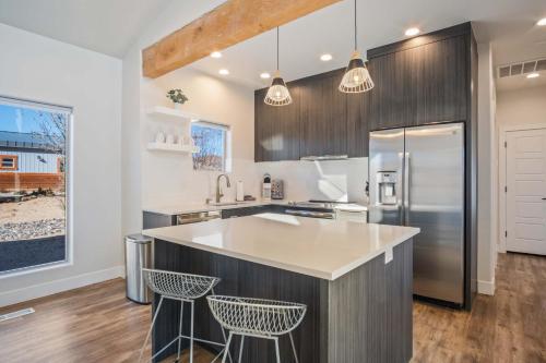 a kitchen with a stainless steel refrigerator and two bar stools at Timber & Tin C 2Bed 2Bath w Pool & Rooftop Deck in Kanab