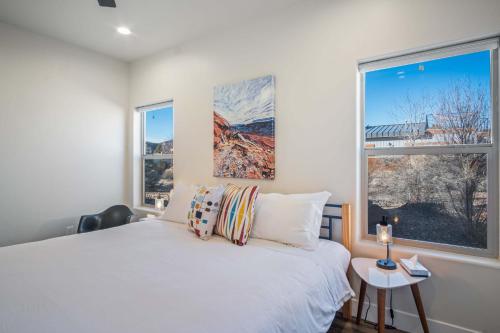 a bedroom with a white bed and two windows at Timber & Tin C 2Bed 2Bath w Pool & Rooftop Deck in Kanab