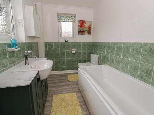 a bathroom with a white tub and a sink at Glanyrafon Smithy in Llandysul