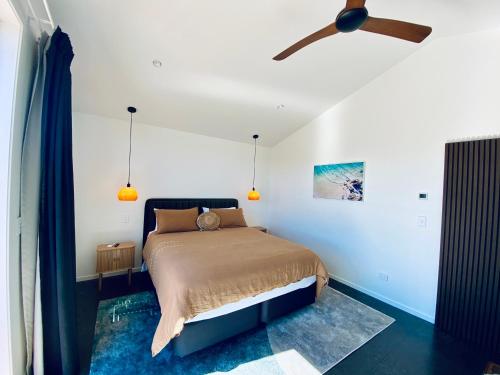 a bedroom with a bed with a ceiling fan at The Modern Alpine Oasis - Mountain Views - Rainfall Shower - Perfect for Couples in Wanaka
