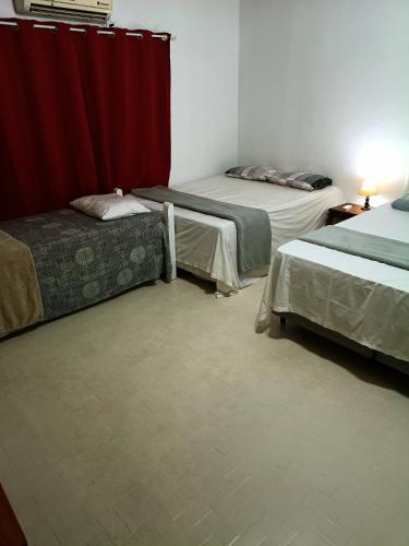 a room with two beds and a red curtain at Posada Dale Dale in São Gabriel