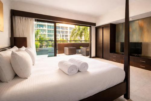 a bedroom with a large bed with two towels at Aldea Thai Studios Steps to Beach and 5th Ave in Playa del Carmen