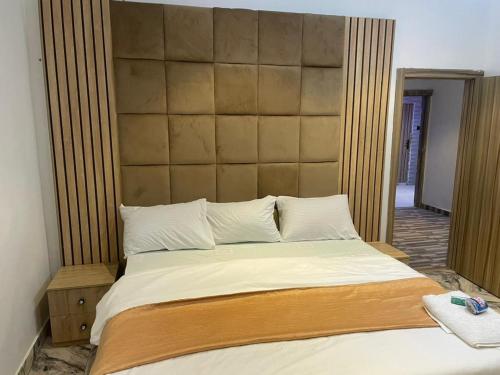 a bedroom with a large bed with a large headboard at Knock inn luxury apartment in Benin City