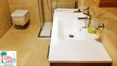 a bathroom with a white sink and a toilet at Apartment Villa Vala in Malinska