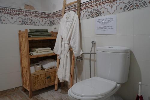 a bathroom with a toilet and a shelf with towels at Bergerie Imsouane in Imsouane