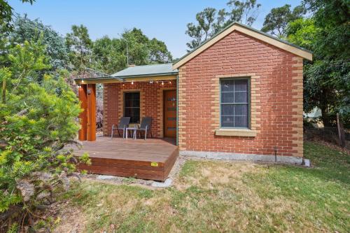 a small brick house with a wooden deck at Ironbark Villa 2 in Halls Gap