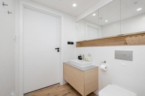 a white bathroom with a sink and a toilet at Apartment with direct sea view in Pobierowo