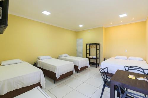 a room with two beds and a table and chairs at Suítes Oásis in Macau