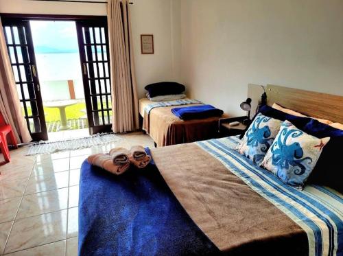 a bedroom with two beds and a balcony at Pousada Praia do Calixto in São Francisco do Sul