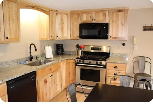 a kitchen with wooden cabinets and a stove and a sink at Mountain View Cottage in Wilmington