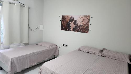 a bedroom with two beds and a picture on the wall at Apt Vista para o Mar in Conde