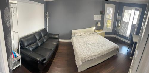 a bedroom with a bed and a leather couch at F1 cozy Sunny room in Mississauga