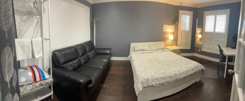 a bedroom with a bed and a leather couch at F1 cozy Sunny room in Mississauga