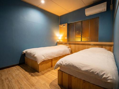 two beds in a room with a blue wall at 山過HOTELs in Chino