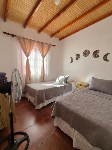 a bedroom with two beds and a fan and a window at Cabañas La Marca in San Pedro de Atacama