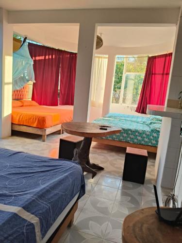ein Schlafzimmer mit zwei Betten, einem Tisch und einem Bett in der Unterkunft Fiesta Zipolite in Zipolite