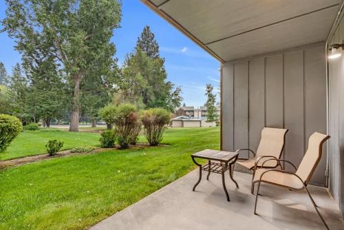 a patio with two chairs and a table and a lawn at First-Floor Downtown Bend Condo in Bend