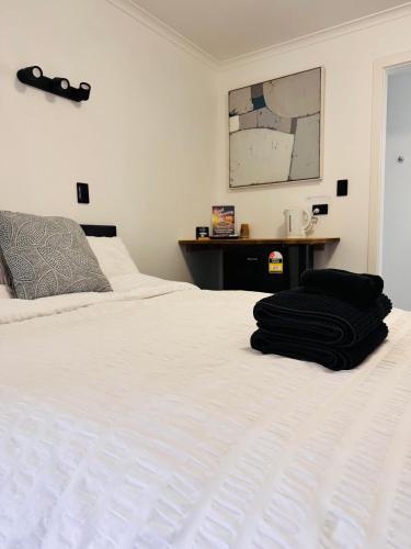 a white bed with two black towels on it at Mount Pleasant Hotel in Mount Pleasant