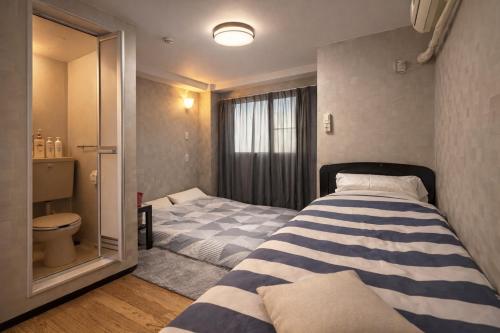 a bedroom with two beds and a toilet at Osaka Umeda West JR Tsukamoto Inn BB in Osaka