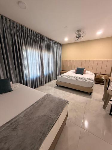 a bedroom with two beds and a large window at Casa Calina Hotel in Caucasia