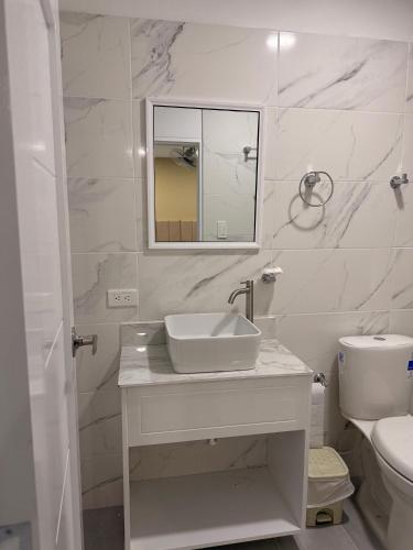 a white bathroom with a sink and a toilet at Casa Calina Hotel in Caucasia