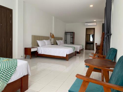 a hotel room with two beds and a table and chairs at Wildbird Hotel in Tràm Chim