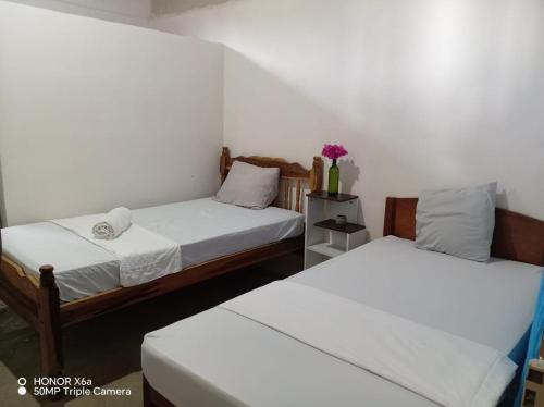 two beds in a room with white walls at Hostal La Cascada San Ramón in Mérida