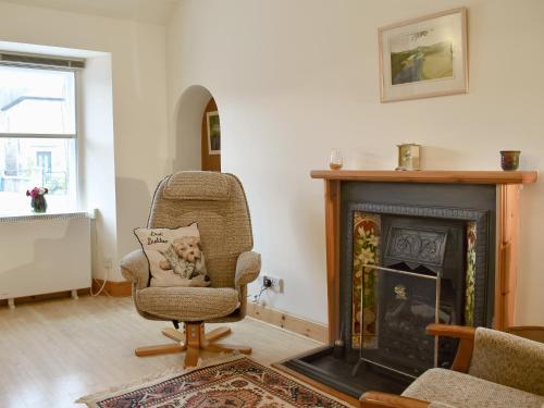 a living room with a chair and a fireplace at Spey Cottage in Aberlour
