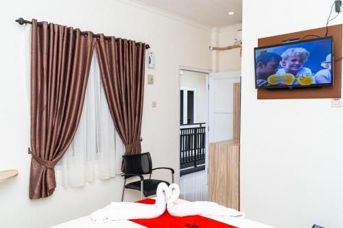 a bedroom with a tv on a wall at L'cost Homestay in Sawah