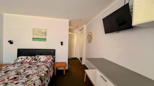 a bedroom with a bed and a flat screen tv at Mandurah Coastal Studio - Pool Outlook in Mandurah