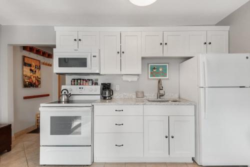 a kitchen with white cabinets and a white refrigerator at Riverfront Studio with Trail access in Bend