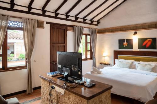 a bedroom with a bed and a desk with a computer at Hacienda Cascanueces in Villa de Leyva