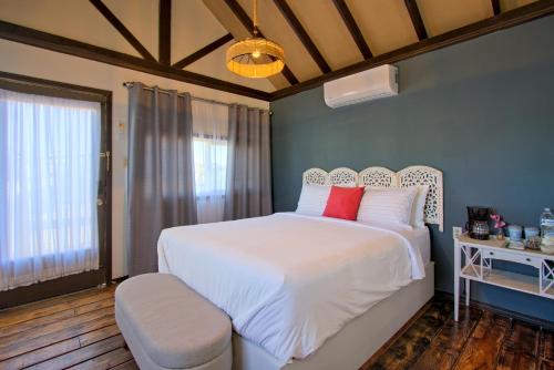 a bedroom with a large white bed with red pillows at 3333 Luz Del Valle Hotel Boutique in Valle de Guadalupe