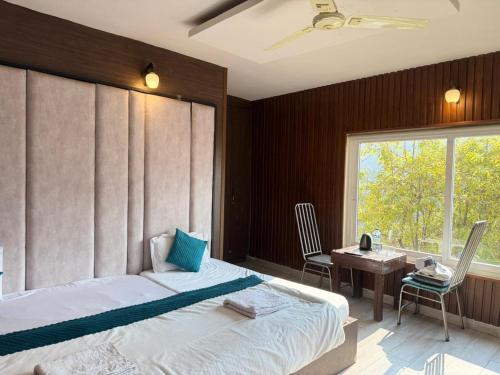 a bedroom with a bed and a desk and a window at Fun N Forest Resort in Dehradun