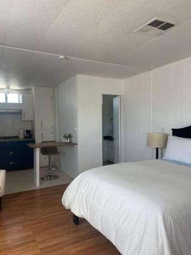 a bedroom with a large white bed and a kitchen at 3333 Luz Del Valle Hotel Boutique in Valle de Guadalupe
